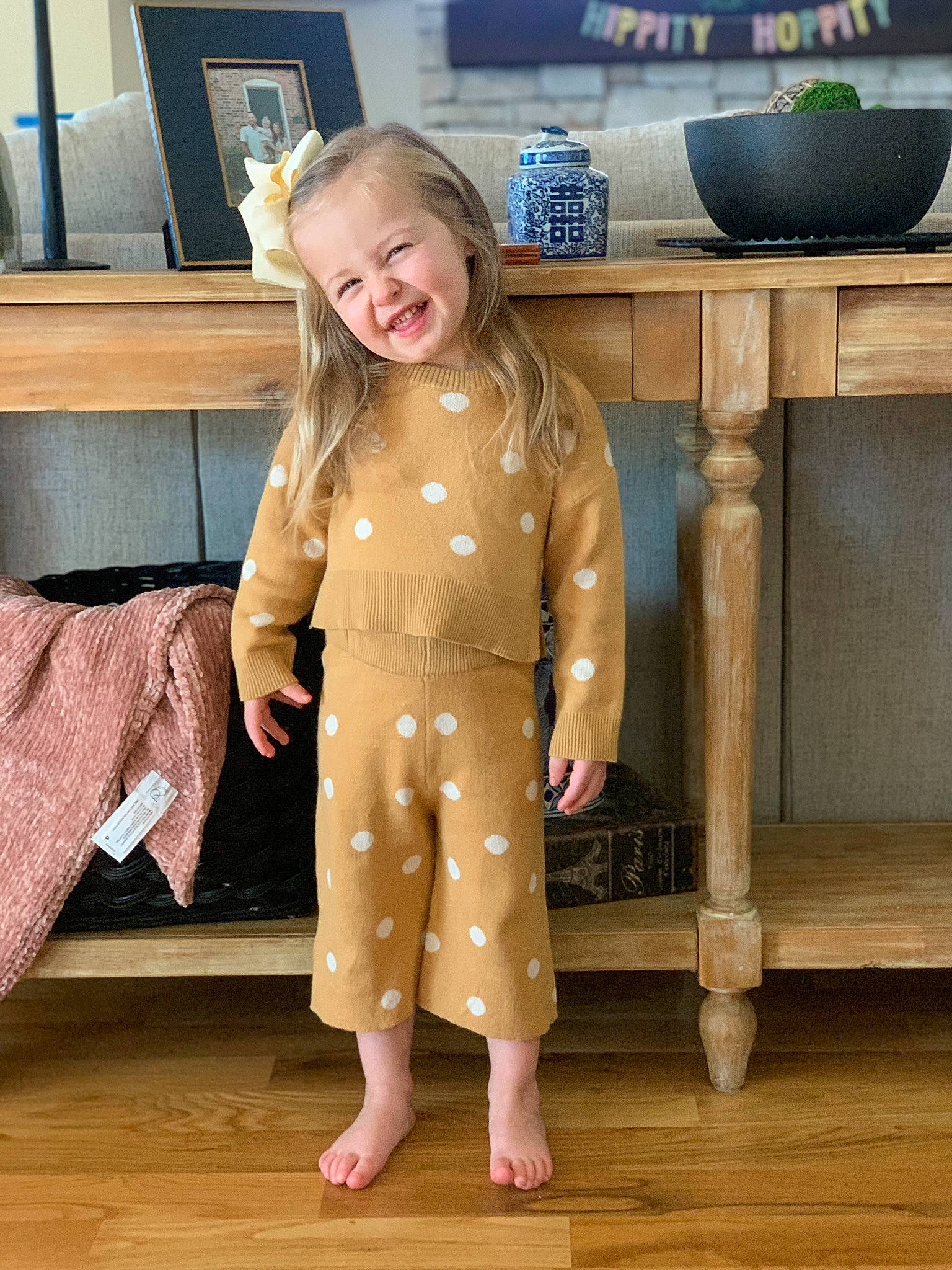 Parker is registered to the contest to win money with this photo: blazer, cabinetry, chair, chest_of_drawers, child, drawer, fashion_design, flooring, formal_wear, fur, hardwood, joy, person, room, sitting, sleeve, smile, standing, table, toddler