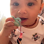 Aaliyah participe au concours pour gagner de l'argent avec cette photo : toddler, child, pacifier, beaded_necklace, cartoon_clothing, minnie_mouse, close_up, cute, baby, indoor, person, hand, face, expression, soft_lighting, casual_wear, curious, infant, portrait, holding
