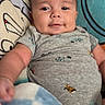 Gabriel joined the competition — help win amazing prizes! baby, infant, smile, onesie, blanket, cushion, indoor, child, face, head, comfort, clothing, person, portrait, seated, cute, young, home, soft, relaxed