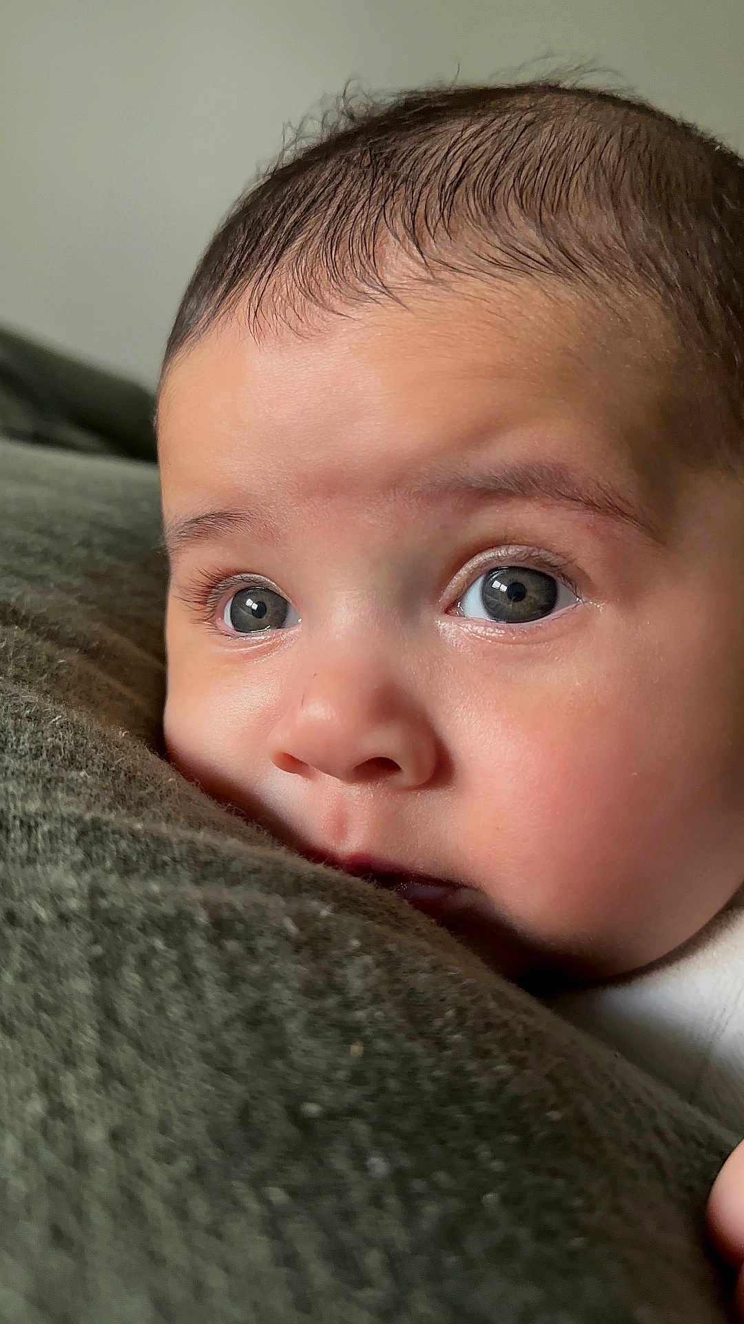 Eloy a rejoint le concours — aidez-le/la à gagner de superbes lots ! baby, close_up, face, eyes, blanket, soft_texture, curious, infant, skin, portrait, child, resting, indoors, young, expression, cute, head, person, warm_light, cozy