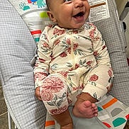 Haylee is registered to the contest to win money with this photo: baby, smiling, floral_pajamas, bouncer, baby_seat, infant, happy, child, foot, hand, indoors, colorful, patterned_clothing, cute, portrait, sitting, playful, comfort, young_child, looking_up