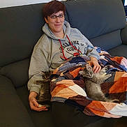 Aka Et Alfi a rejoint le concours — aidez-le/la à gagner de superbes lots ! animal, blanket, casual, cat, comfort, couch, cozy, friendship, fur, glasses, home, hoodie, indoor, kitten, person, pet, relaxing, resting, seated, smile