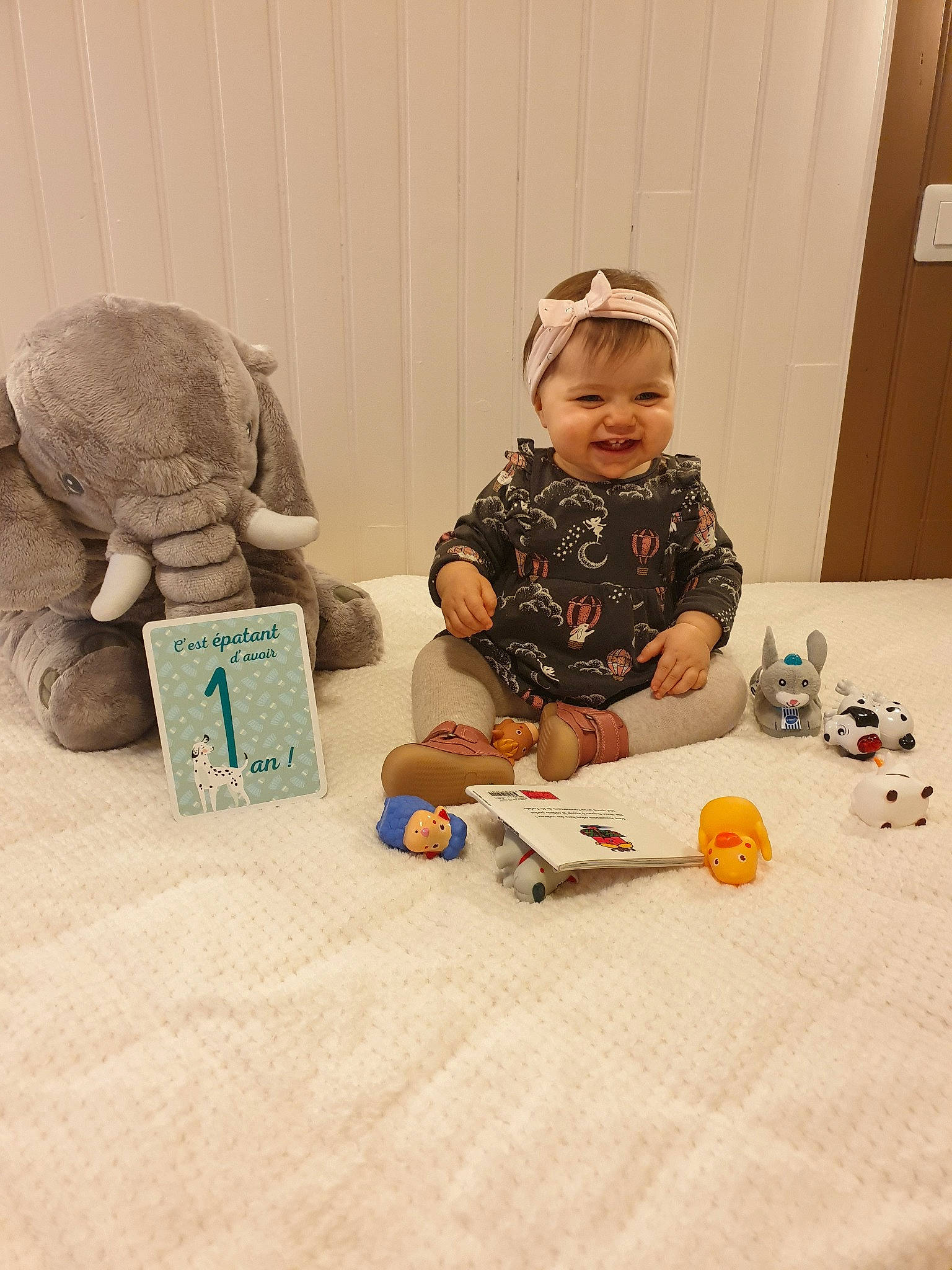 Elya participe au concours pour gagner de l'argent avec cette photo : baby, baby_toddler_clothing, cap, child, comfort, flooring, fun, hat, human, mammal, paper_product, person, play, room, sitting, sleeve, smile, toddler, toy, wood