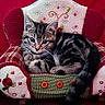 kitten, cat, tabby, animal, pet, plush_chair, red_background, cozy, cute, feline, curious, fur, small, indoor, resting, decorative, buttons, embroidered, soft, comfortable