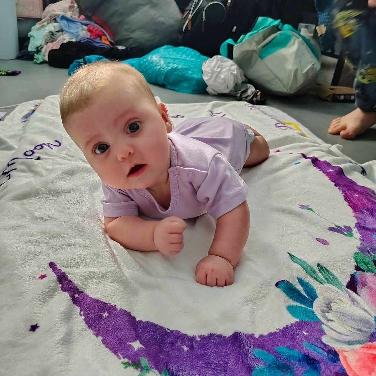Morgna joined the competition — help win amazing prizes! baby, background, bag, blanket, child, clothing, crescent_moon, curious, expression, face, floor, floral, foot, hand, indoors, infant, onesie, person, pile_of_clothes, purple