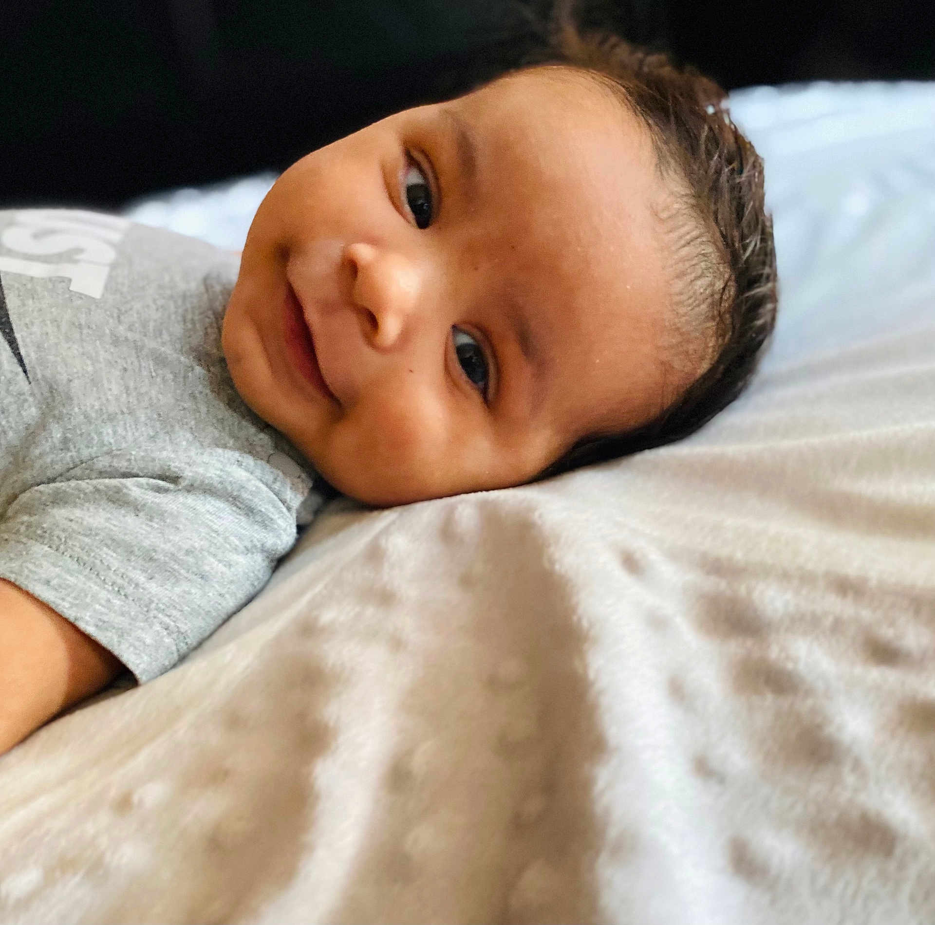 Zayne joined the competition — help win amazing prizes! baby, smile, face, infant, blanket, clothing, lying_down, cute, portrait, young_child, happy, skin, head, eyes, soft_texture, indoors, cozy, closeup, person, child