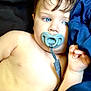 baby, child, pacifier, blue_eyes, close_up, infant, skin, hand, portrait, lying_down, blue_fabric, straps, cute, young, face, expression, indoors, soft_light, resting, sleepy