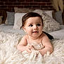 Cash is registered to the contest to win money with this photo: baby, infant, child, blue_eyes, dark_hair, blanket, soft_texture, bedroom, pillow, brick_wall, cute, smiling, curious, hands, lying_down, indoor, warm_lighting, cozy, skin, portrait
