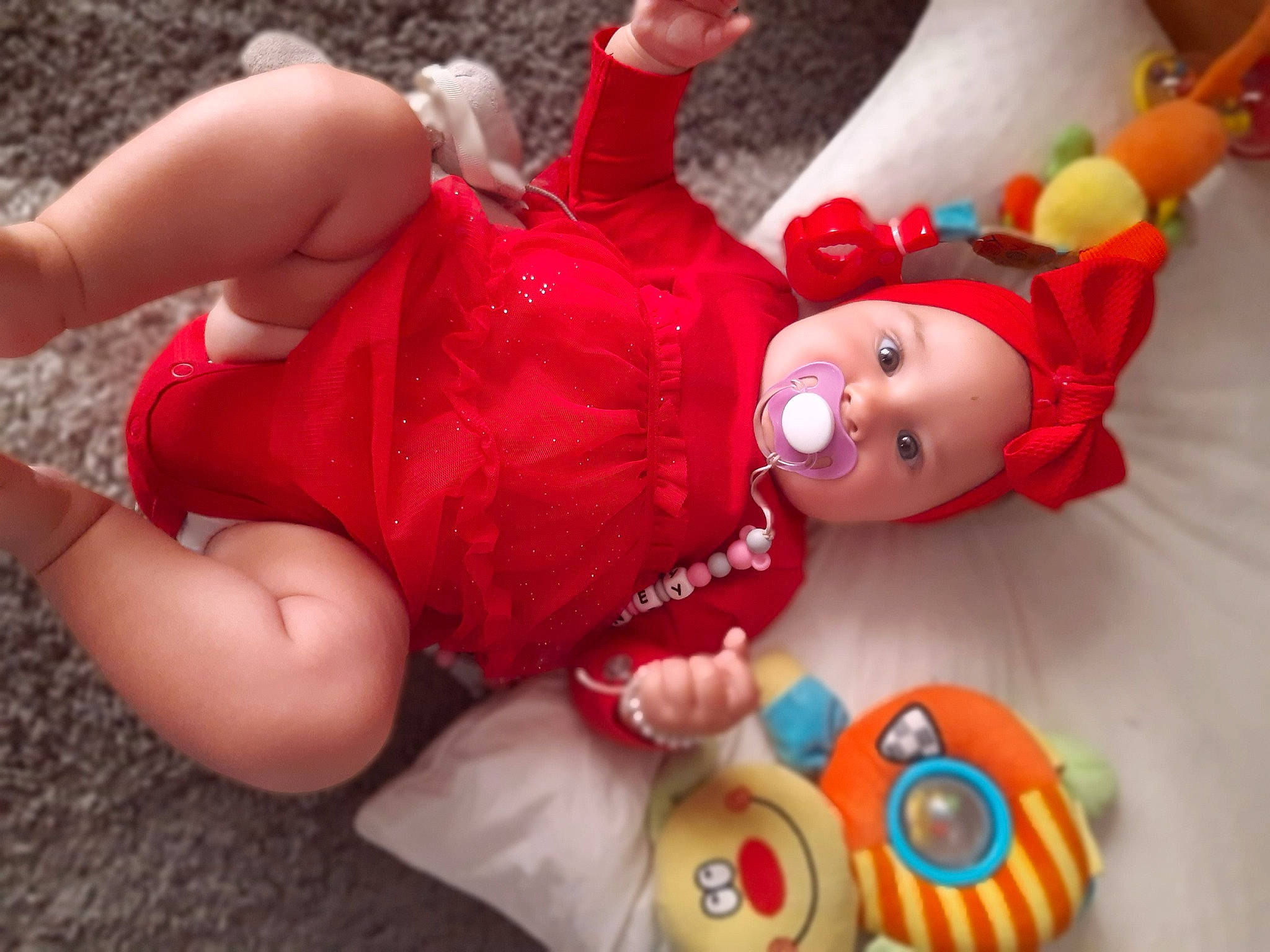 Whitney participe au concours pour gagner de l'argent avec cette photo : arm, baby, child, doll, facial_expression, finger, fun, gesture, happy, headwear, human_body, joint, leg, orange, organ, person, product, red, textile, thigh