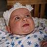 Lila a rejoint le concours — aidez-le/la à gagner de superbes lots ! baby, infant, face, headband, flower, clothing, blue_flower_pattern, white_outfit, closeup, portrait, child, cute, soft_lighting, indoor, wooden_background, expression, skin, hand, newborn, adorable