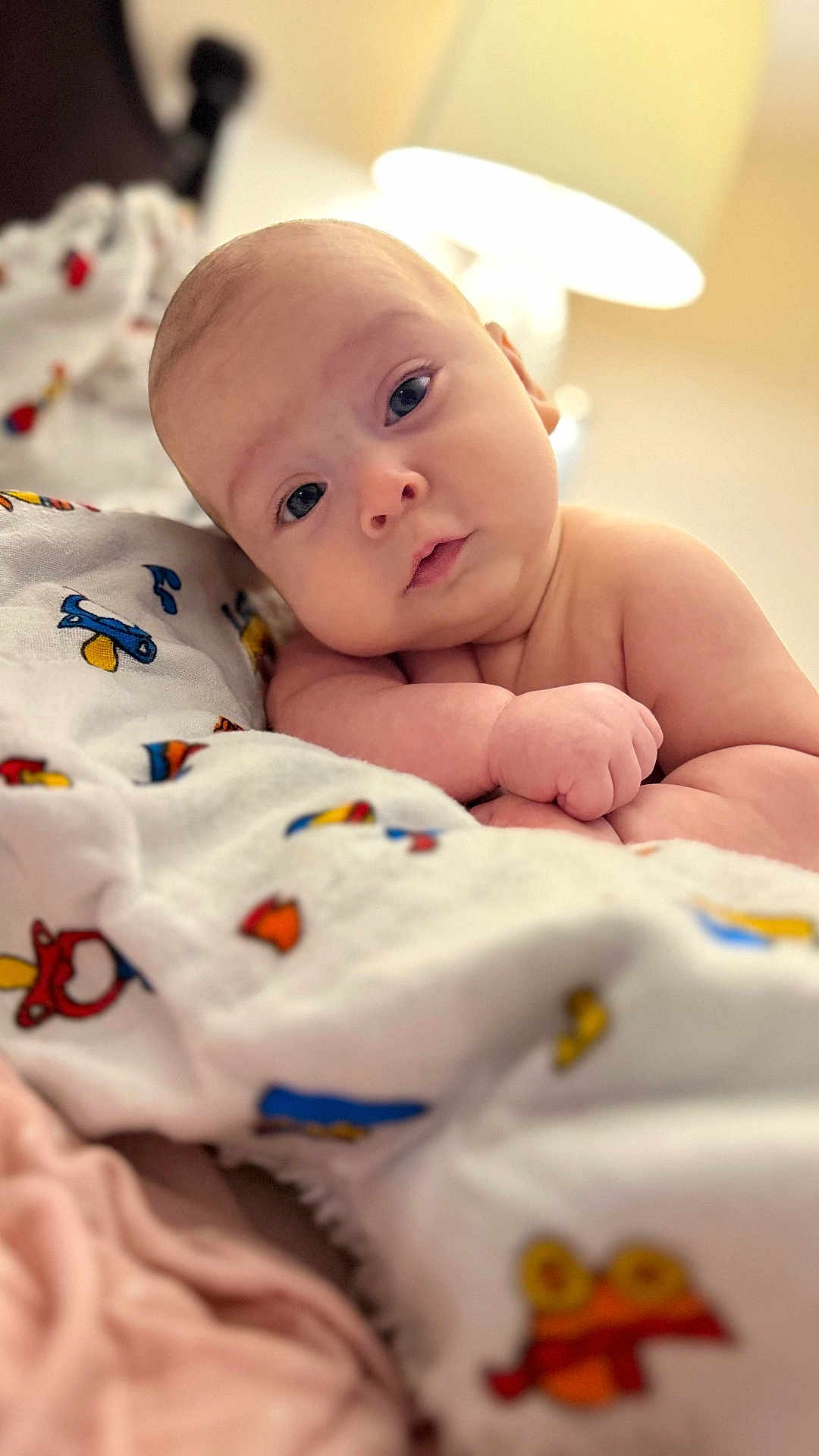 Maria is registered to the contest to win money with this photo: baby, infant, blanket, cartoon, colorful, cute, face, expression, gaze, head, indoors, lamp, lighting, looking, person, portrait, resting, skin, soft, toddler