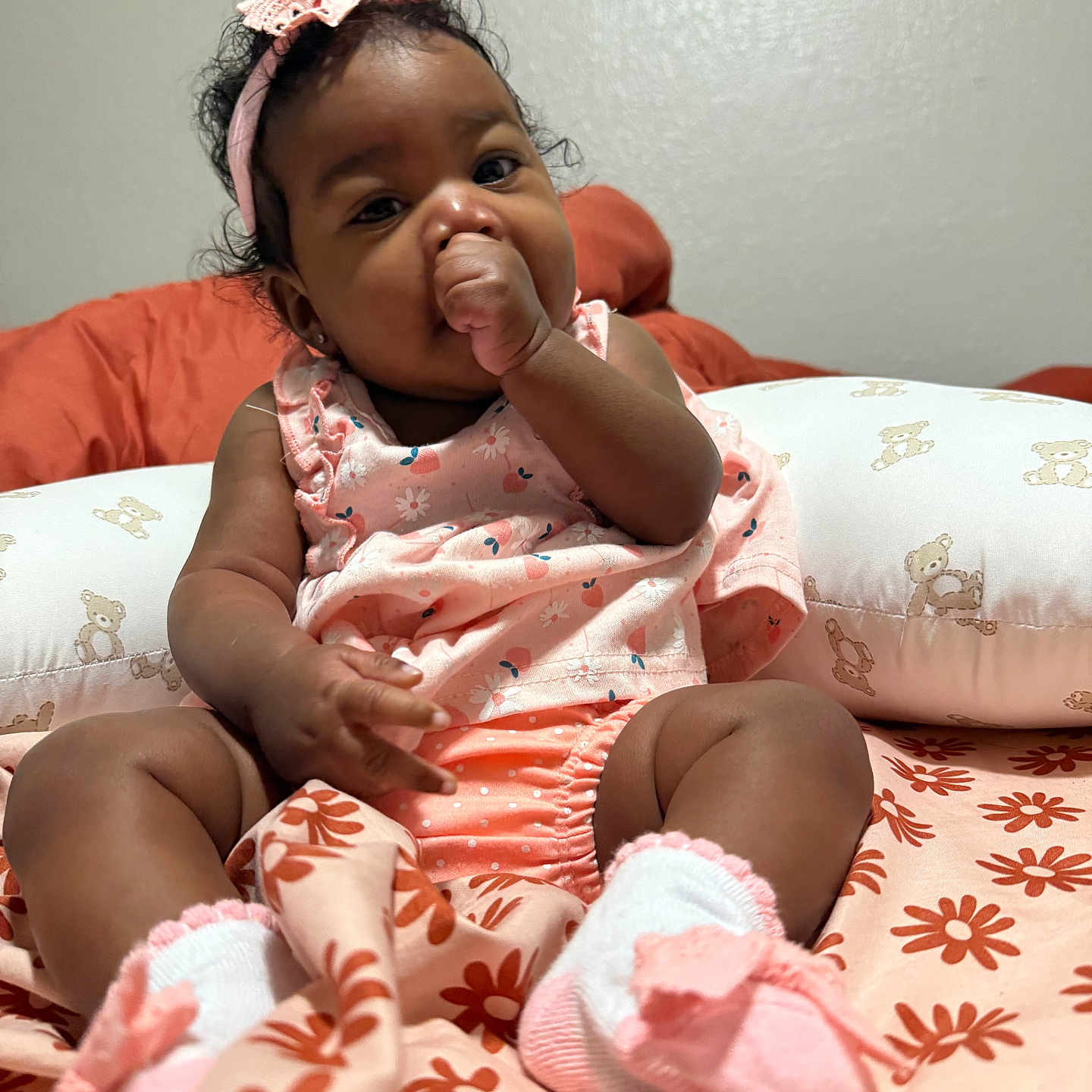 Schrhyia joined the competition — help win amazing prizes! baby, infant, child, thumb_sucking, pink_clothing, headband, sock, blanket, floral_pattern, pillow, teddy_bear, cute, indoors, portrait, sitting, curly_hair, soft_lighting, young_child, comfort, adorable