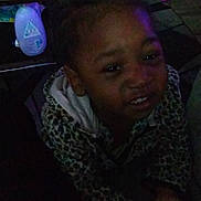 Kalani is registered to the contest to win money with this photo: child, girl, indoor, dark, beads, hair, jacket, patterned_clothing, smile, plastic_chair, table, bottle, floor, toy, furniture, person, young, portrait, home, casual