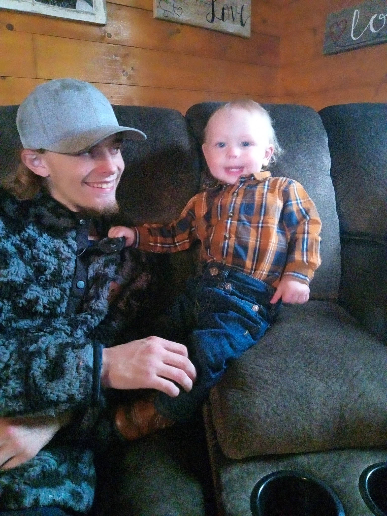 Klayton joined the competition — help win amazing prizes! baby, baseball_cap, cap, child, comfort, couch, event, eye, fun, headwear, joy, lap, living_room, military_camouflage, pattern, person, picture_frame, plaid, sitting, skin