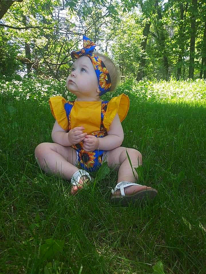 Melani is registered to the contest to win money with this photo: child, fawn, grass, headwear, meadow, person, plant, sitting, summer