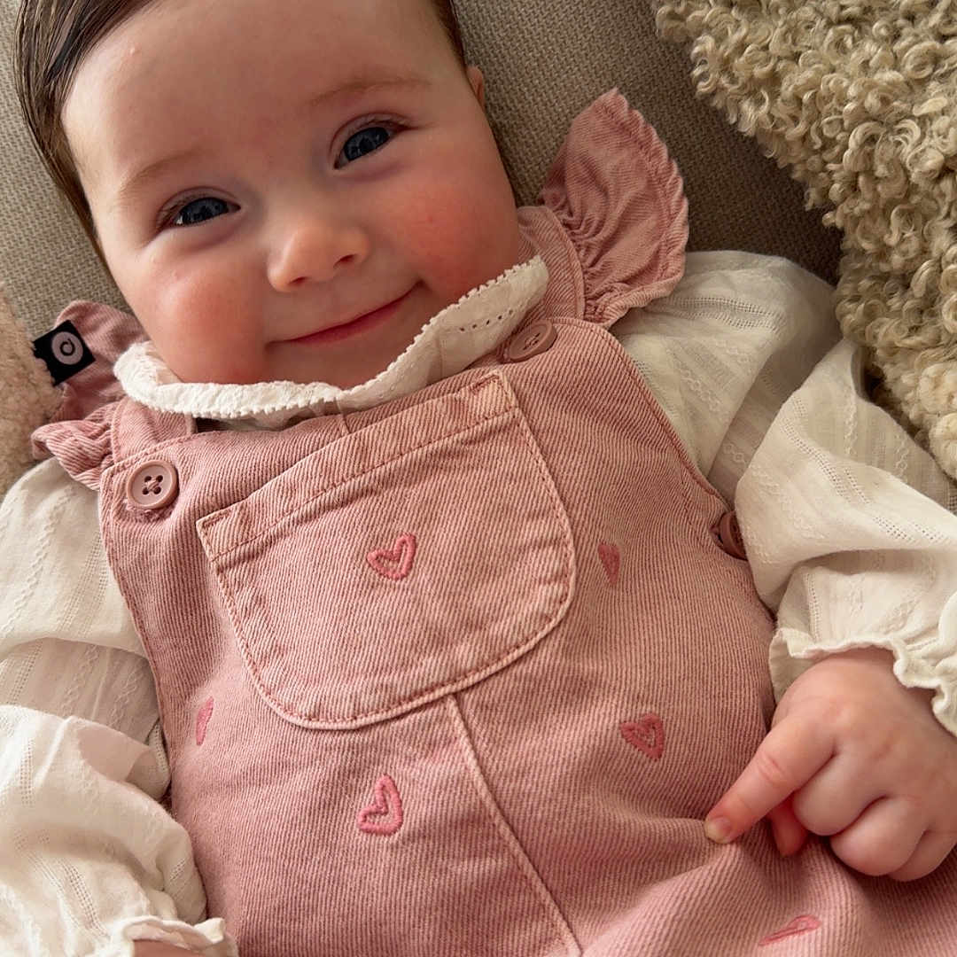 Victoria a rejoint le concours — aidez-le/la à gagner de superbes lots ! baby, child, infant, smile, pink_dress, hearts, couch, cozy, cute, happy, face, portrait, clothing, indoor, person, sitting, hand, fingers, soft, warm