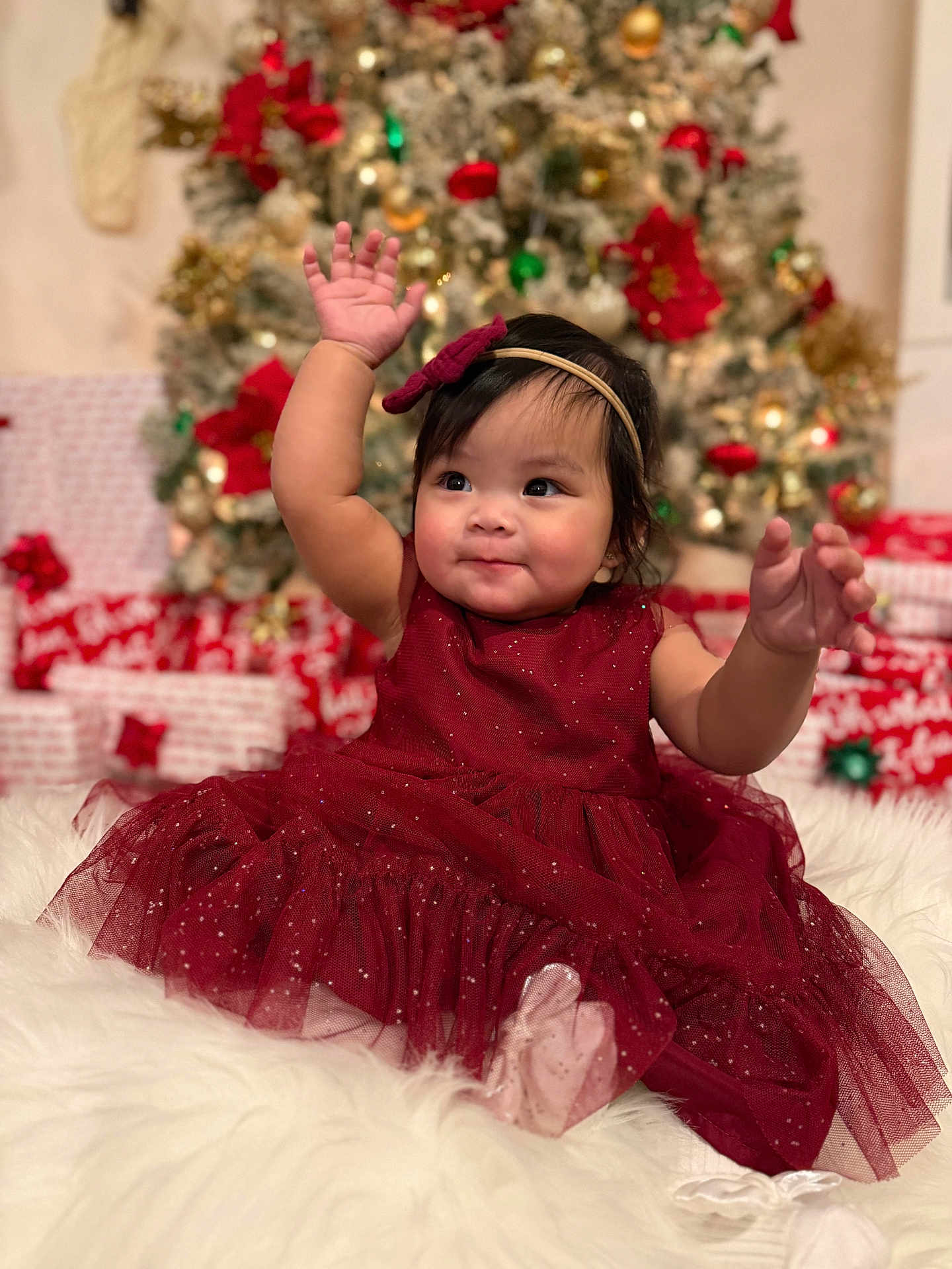 Scarlett joined the competition — help win amazing prizes! baby, child, dress, red_dress, headband, christmas_tree, presents, holiday, celebration, smile, happy, indoors, festive, fluffy_surface, cute, girl, portrait, holiday_decor, sparkle, raising_hands