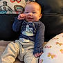 baby, infant, smile, clothing, blanket, cushion, indoor, happy, face, person, sitting, soft, cute, winter, cozy, pattern, blue_shirt, gray_pants, child, comfort
