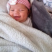 Enyarayne is registered to the contest to win money with this photo: baby, smiling, blanket, headband, bow, pink, white, cozy, wrapped, face, infant, cute, soft, texture, fabric, child, portrait, happy, lying_down, homedecor
