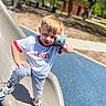 child, boy, playground, slide, plush_toy, sneakers, casual_clothing, white_tshirt, gray_pants, outdoor, daylight, smiling, blond_hair, park, trees, sunny, fun, cute, pose, recreation