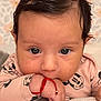 baby, infant, face, hand, clothing, mickey_mouse, bracelet, pink, cute, portrait, close_up, child, sleeve, skin, black_hair, young, expression, lying_down, pattern, background