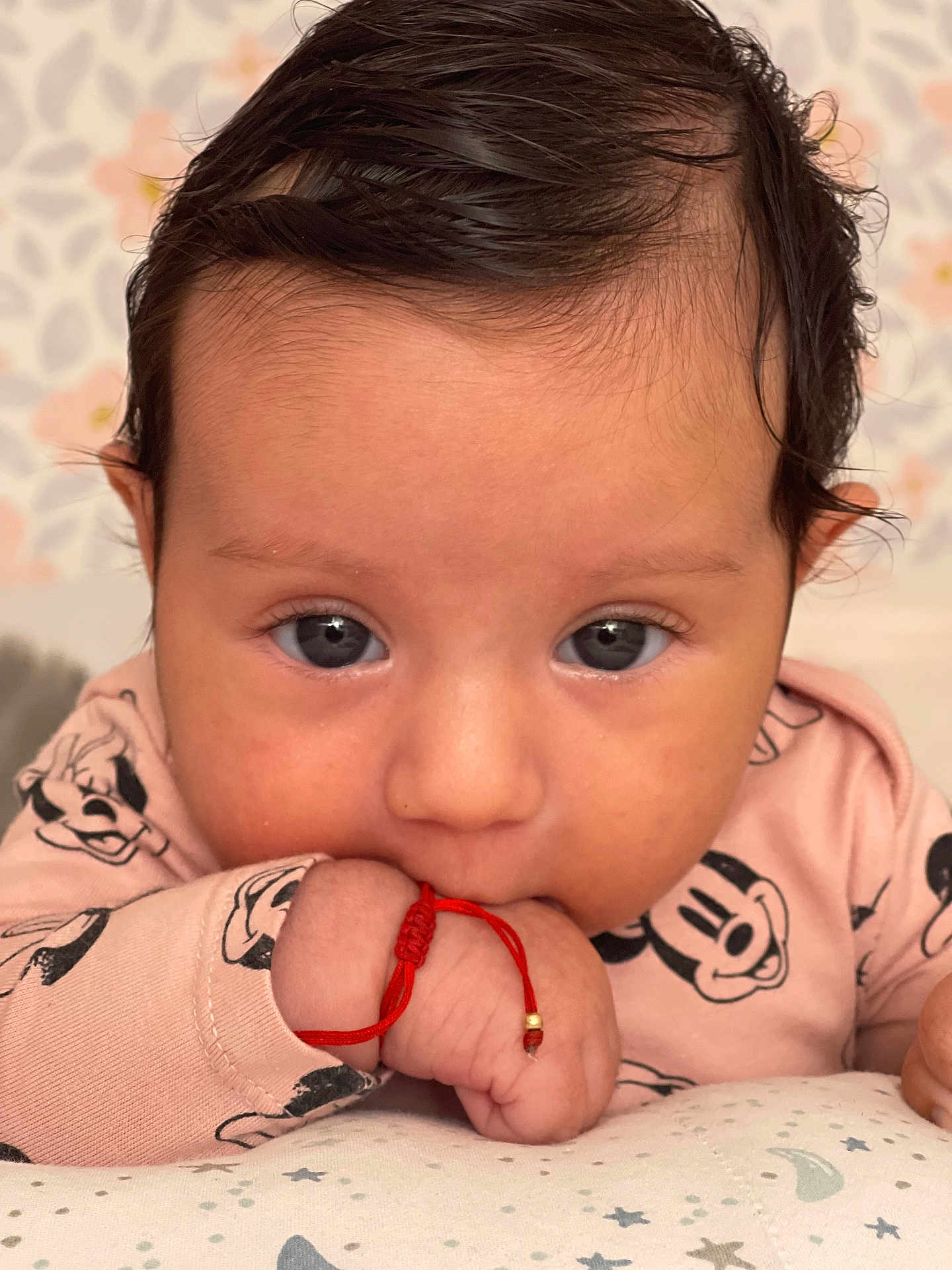 Myra a rejoint le concours — aidez-le/la à gagner de superbes lots ! baby, infant, face, hand, clothing, mickey_mouse, bracelet, pink, cute, portrait, close_up, child, sleeve, skin, black_hair, young, expression, lying_down, pattern, background