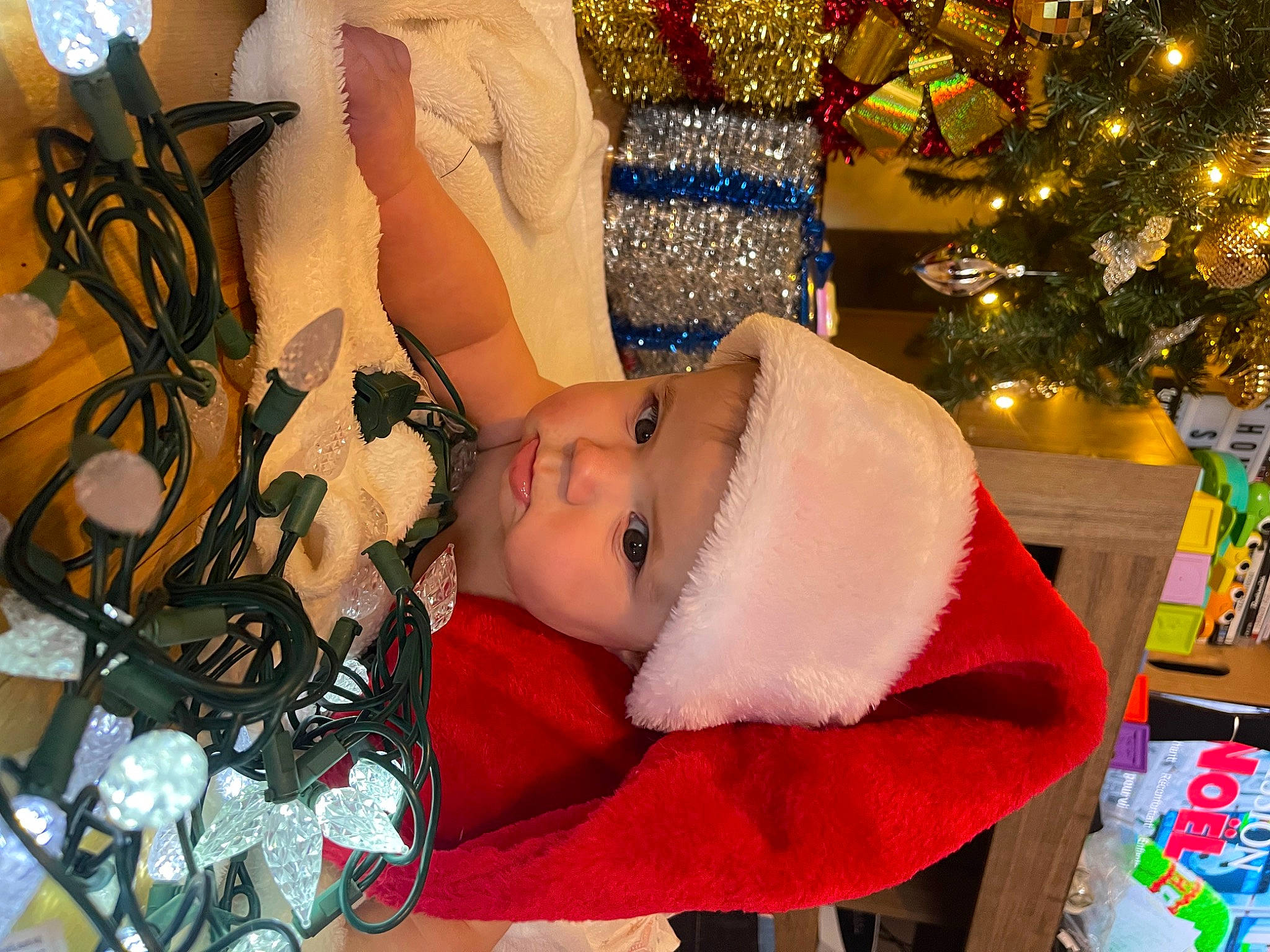 Lyannah a rejoint le concours — aidez-le/la à gagner de superbes lots ! baby, baby_toddler_clothing, carmine, child, christmas, christmas_decoration, christmas_eve, christmas_ornament, christmas_tree, event, fun, fur, happy, headwear, holiday, ornament, person, room, rose, toddler