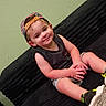 toddler, child, boy, cap, backwards_cap, smile, sitting, couch, black_couch, green_wall, shorts, sleeveless_shirt, sneakers, happy, indoor, portrait, casual, cute, furniture, person