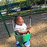 car, child, clothing, daytime, fence, fun, grass, happiness, joy, motion, outdoor, playground, shoes, smile, summer, sunlight, swing, toddler, trees, woodchips