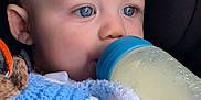 Brodie is registered to the contest to win money with this photo: baby, blanket, blue_eyes, bottle, child, close_up, cozy, cute, drinking, face, hand, indoor, infant, knitted_blanket, looking_away, peaceful, person, portrait, soft_lighting, young_child
