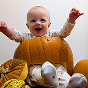 Brodie joined the competition — help win amazing prizes! baby, pumpkin, halloween, smiling, child, gourd, orange, white_clothing, joyful, cute, celebration, autumn, holiday, festive, sitting, indoor, happy, face, hands, feet