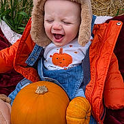 Brodie joined the competition — help win amazing prizes! baby, child, pumpkin, orange_jacket, hat, denim_overalls, laughing, fall, autumn, cute, outdoor, plants, blanket, seasonal, happy, smiling, cozy, clothing, person, toddler