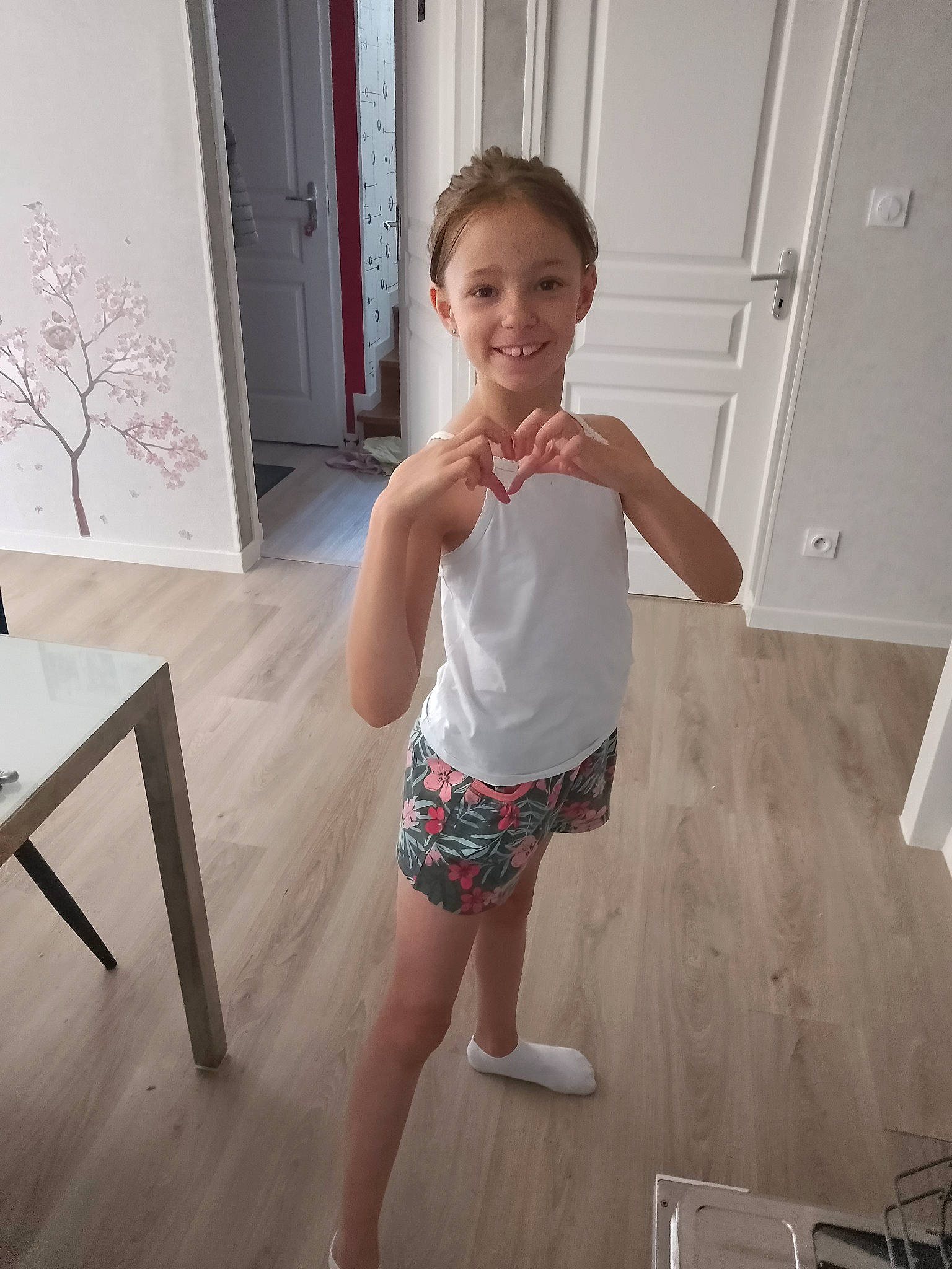 Maëlys participe au concours pour gagner de l'argent avec cette photo : barefoot, door, floor, flooring, fun, happy, hardwood, human_leg, joint, joy, knee, leg, person, shorts, sleeve, smile, standing, thigh, toddler, trunk