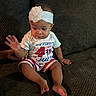 Nevaeh joined the competition — help win amazing prizes! baby, child, infant, sitting, couch, clothing, headband, flower, hand, foot, red_white_blue, holiday, 4th_of_july, celebration, indoors, person, cute, happy, portrait, texture