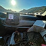 cat, tabby_cat, sleeping, car_interior, dashboard, navigation_screen, sunlight, highway, scenic_view, person_arm, travel, road_trip, seat, window, nature, hills, blue_sky, leisure, resting, pet