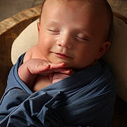 Conal is registered to the contest to win money with this photo: baby, infant, sleeping, wrapped, blue_cloth, peaceful, smile, face, head, newborn, soft_lighting, portrait, closeup, cute, child, hands, wooden_background, cozy, resting, peaceful_expression