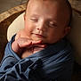 baby, infant, sleeping, wrapped, blue_cloth, peaceful, smile, face, head, newborn, soft_lighting, portrait, closeup, cute, child, hands, wooden_background, cozy, resting, peaceful_expression