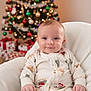 baby, child, smiling, christmas_tree, holiday, pajamas, chair, present, gift, decorations, ornaments, indoor, festive, seasonal, portrait, cute, happy, cozy, background_blur, celebration