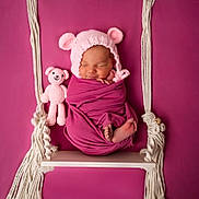 Sienna a rejoint le concours — aidez-le/la à gagner de superbes lots ! newborn, baby, sleeping, knit_hat, pink, magenta, swing, rope, crocheted_toy, teddy_bear, wrapped, infant, cute, studio_photo, portrait, soft_lighting, peaceful, child, small_feet, cozy