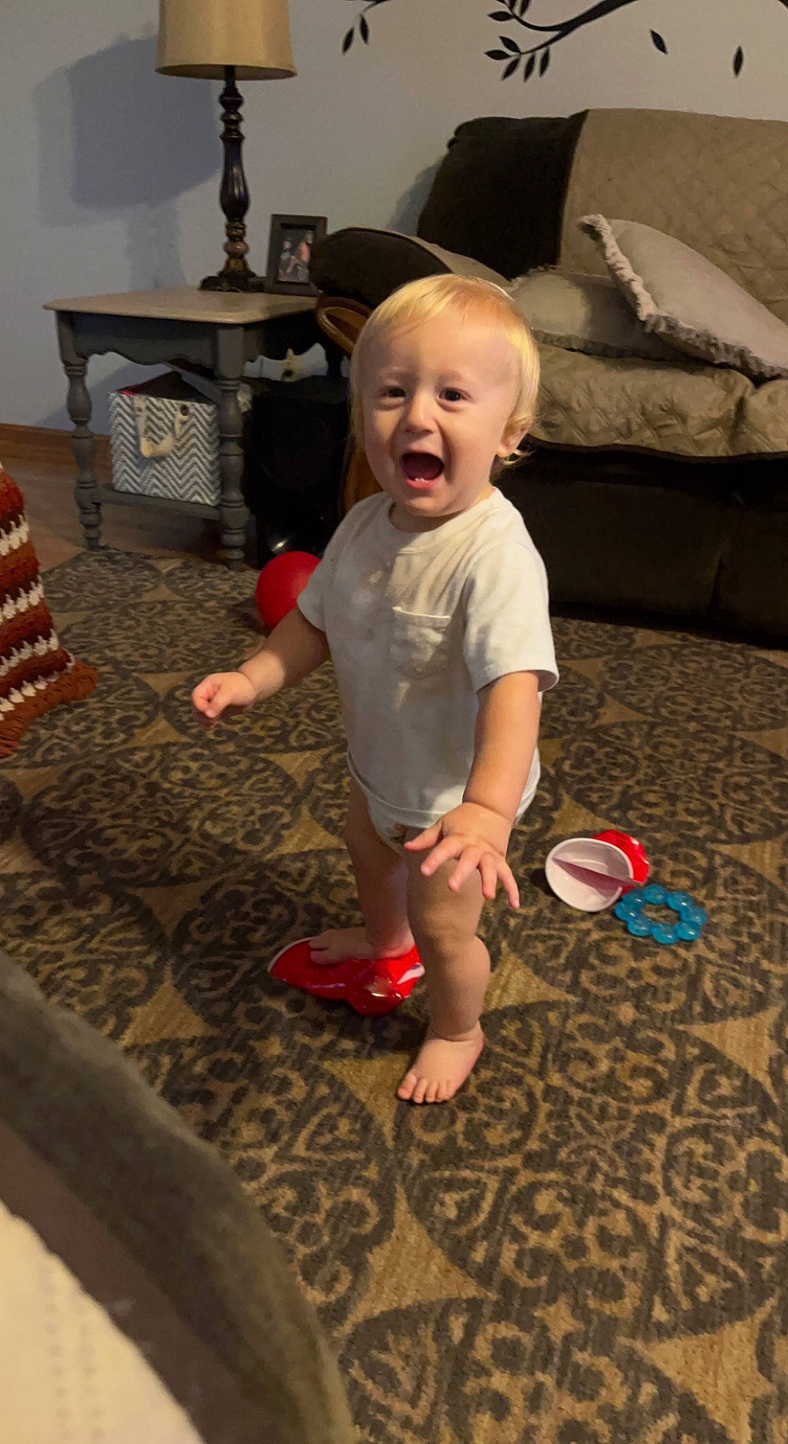Christian is registered to the contest to win money with this photo: baby, baby_toddler_clothing, barefoot, child, event, floor, flooring, foot, fun, leg, living_room, person, room, sitting, skin, smile, standing, t_shirt, table, toddler