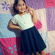 Amaryllis is registered to the contest to win money with this photo: casual, child, colorful_background, cute, dress, fashion, floor, girl, happy, heart_icon, indoors, necklace, playful, portrait, pose, quilt, smiling, standing, white_shoes, young
