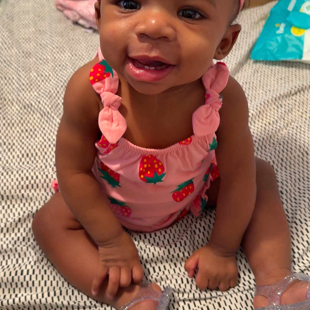 Amazyn joined the competition — help win amazing prizes! baby, bedspread, bow, child, cute, face, girl, hands, happy, headband, indoor, infant, legs, pink_clothing, room, shoes, sitting, smiling, sparkly_shoes, strawberry_pattern
