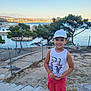 Aylan participe au concours pour gagner de l'argent avec cette photo : boy, cap, child, cityscape, daytime, fence, happy, nature, outdoor, rocks, sand, sea, shorts, sky, smiling, stairs, sunlight, tank_top, trees, water
