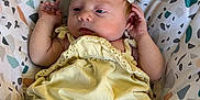 Maggie joined the competition — help win amazing prizes! baby, infant, child, yellow_outfit, headband, floral_headband, patterned_seat, colorful_background, barefoot, small_hands, small_feet, relaxed, indoors, portrait, cute, young, sitting, comfortable, soft_lighting, skin