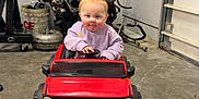 Maggie joined the competition — help win amazing prizes! toddler, child, toy_car, red_car, garage, mechanical_parts, concrete_floor, purple_hair_tie, sweater, baby, indoor, vehicle, play, cute, smile, small_car, face, person, head, hands