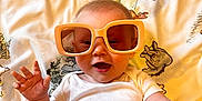 Hailey joined the competition — help win amazing prizes! baby, child, sunglasses, white_onesie, blanket, animal_print, carpet, smile, happy, indoor, cute, infant, playful, fashion, accessory, portrait, person, relaxing, fun, light