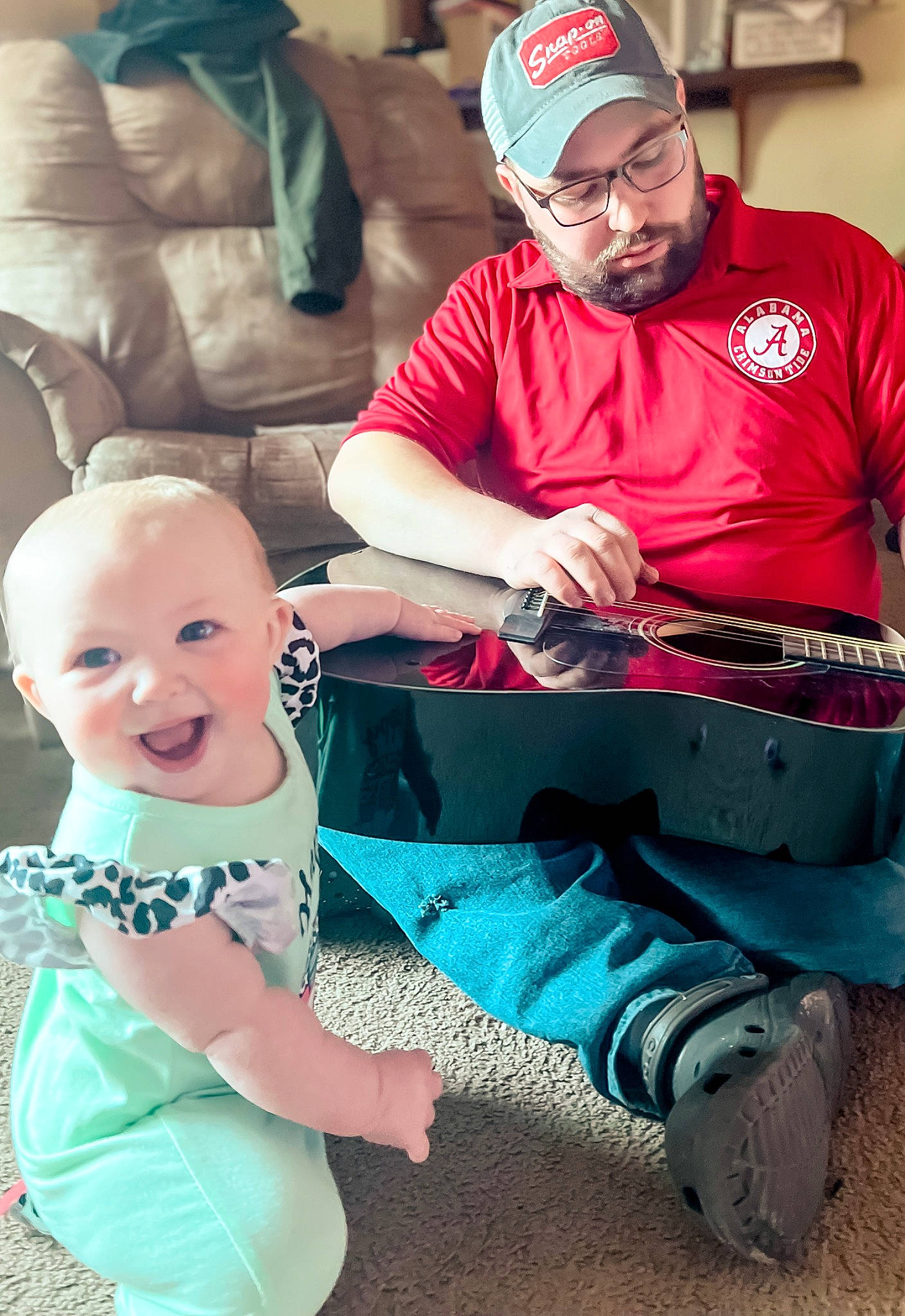 Jessica is registered to the contest to win money with this photo: arm, baby_toddler_clothing, cap, child, event, facial_expression, fun, green, happy, headwear, human, lap, leisure, musical_instrument, organ, person, product, sitting, smile, t_shirt