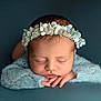 newborn, baby, sleeping, flower_crown, headband, blue, knitted, soft, peaceful, portrait, infant, cute, resting, closeup, hands, face, young_child, studio, cozy, calm