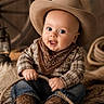 baby, child, cowboy, hat, bandana, plaid_shirt, jeans, boots, rope, fur_rug, lantern, wagon_wheel, portrait, smiling, indoor, cute, western, rustic, sitting, hands