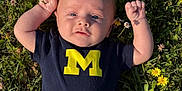 Grayson joined the competition — help win amazing prizes! baby, infant, grass, flowers, outdoor, sunlight, blue_shirt, yellow_letter, cute, child, nature, plant, clothing, portrait, person, fist, summer, field, green, happy